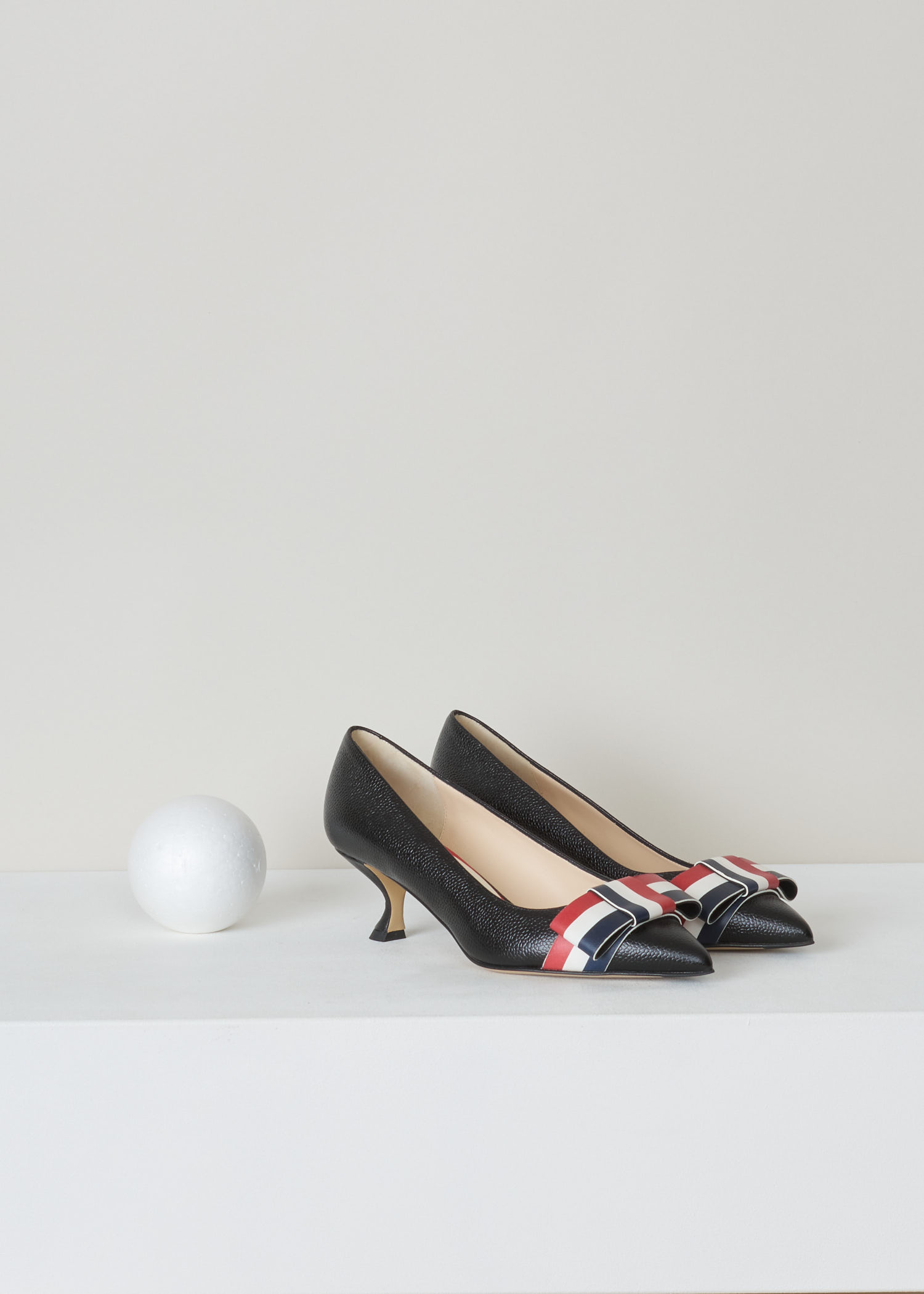 Thom Browne, Curved queenie heel pump, FFH121A_03542_001_black, black, front. High quality leather tooled until it got this beautiful pebble grain motive. As most of the Thom Browne items this gorgeous queenie heels pump also comes with the infamous rwb colours in the shape of a bow on the vamp of the shoe.   

heel height: 5 cm / 2 inch. 