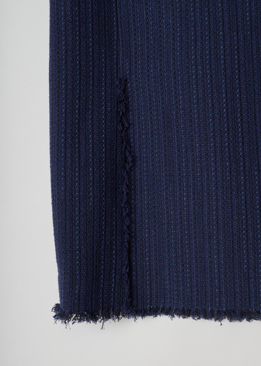 Thom Browne, Blue knitted pencil skirt, FGC452T_04529_415_navy, blue, detail. Starting from the top this lovely pencil skirt has raw frilled edges. Zipper on the side for fastening. Also the hem is similarly unfinished and has frills hanging off. On the back this model has two splits.
