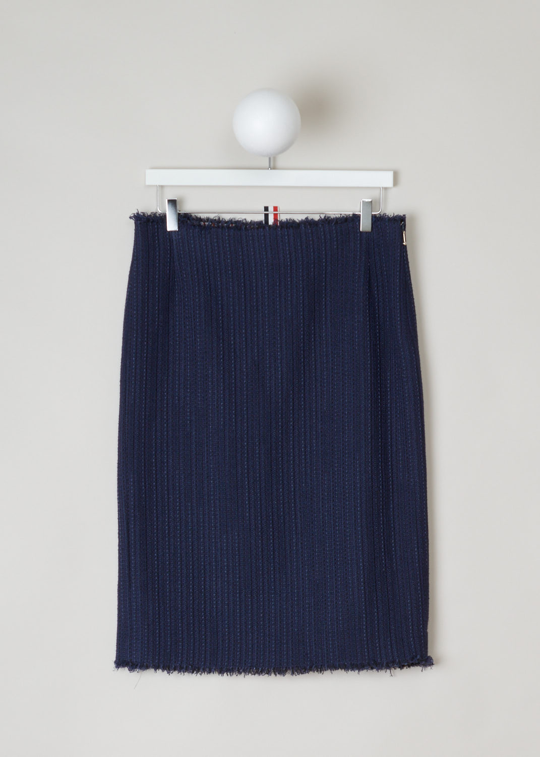 Thom Browne, Blue knitted pencil skirt, FGC452T_04529_415_navy, blue, front. Starting from the top this lovely pencil skirt has raw frilled edges. Zipper on the side for fastening. Also the hem is similarly unfinished and has frills hanging off. On the back this model has two splits.