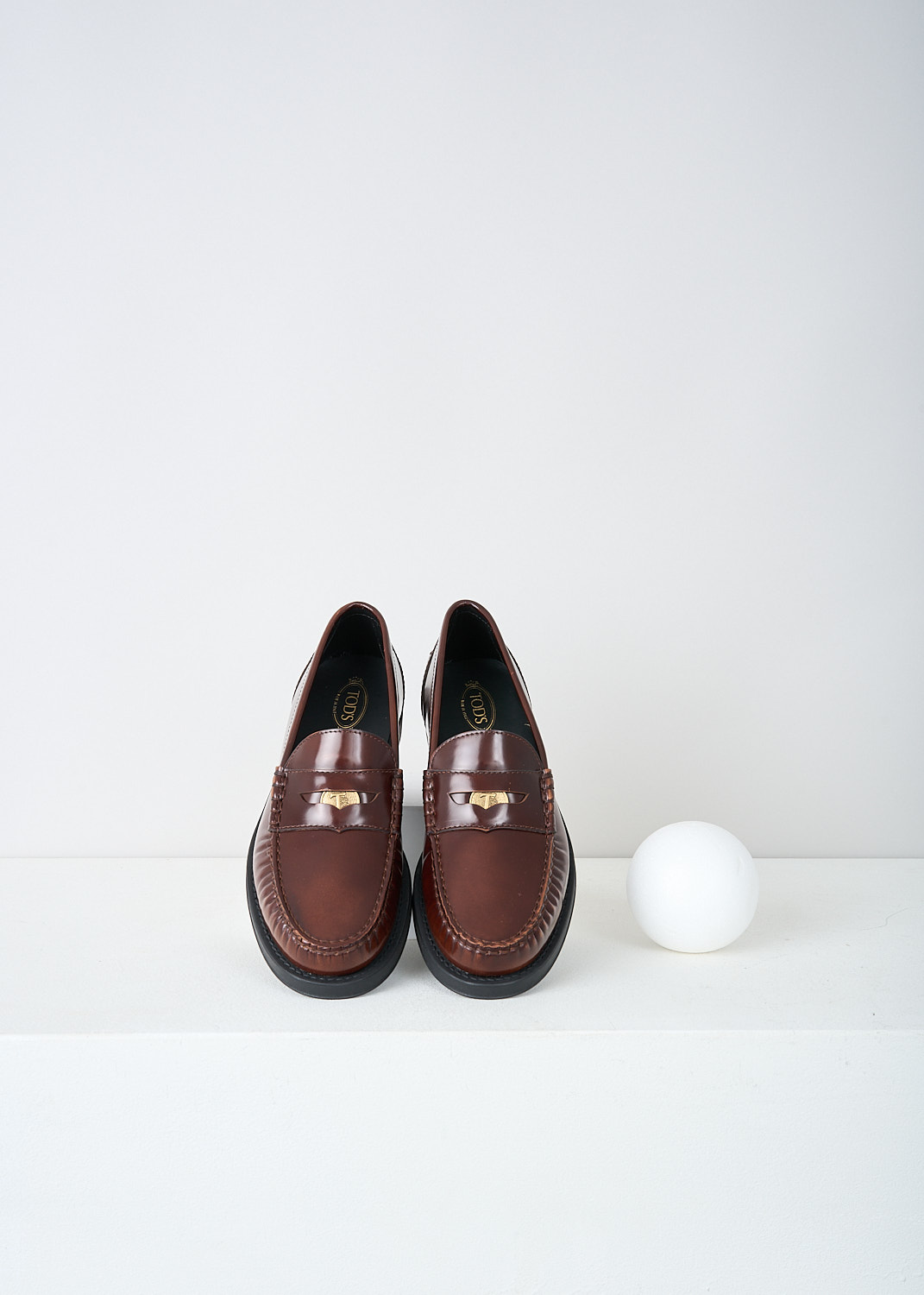 Tods, Brown leather penny loafers, XXW02I0EP00SHAS003, Brown, Top, These brown leather slip-on penny loafers have a rounded toe and a slotted leather strip with a decorative coin over the upper side. Around the trim, the leather is subtly pleated. These loafers have black soles.
  
