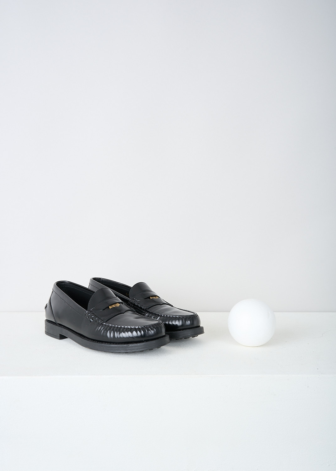 Tods, Black leather penny loafers, XXW02I0EP00SHAB999, Black, Front, These black leather slip-on penny loafers have a rounded toe and a slotted leather strip with a decorative coin over the upper side. Around the trim, the leather is subtly pleated. These loafers have black soles.
  

