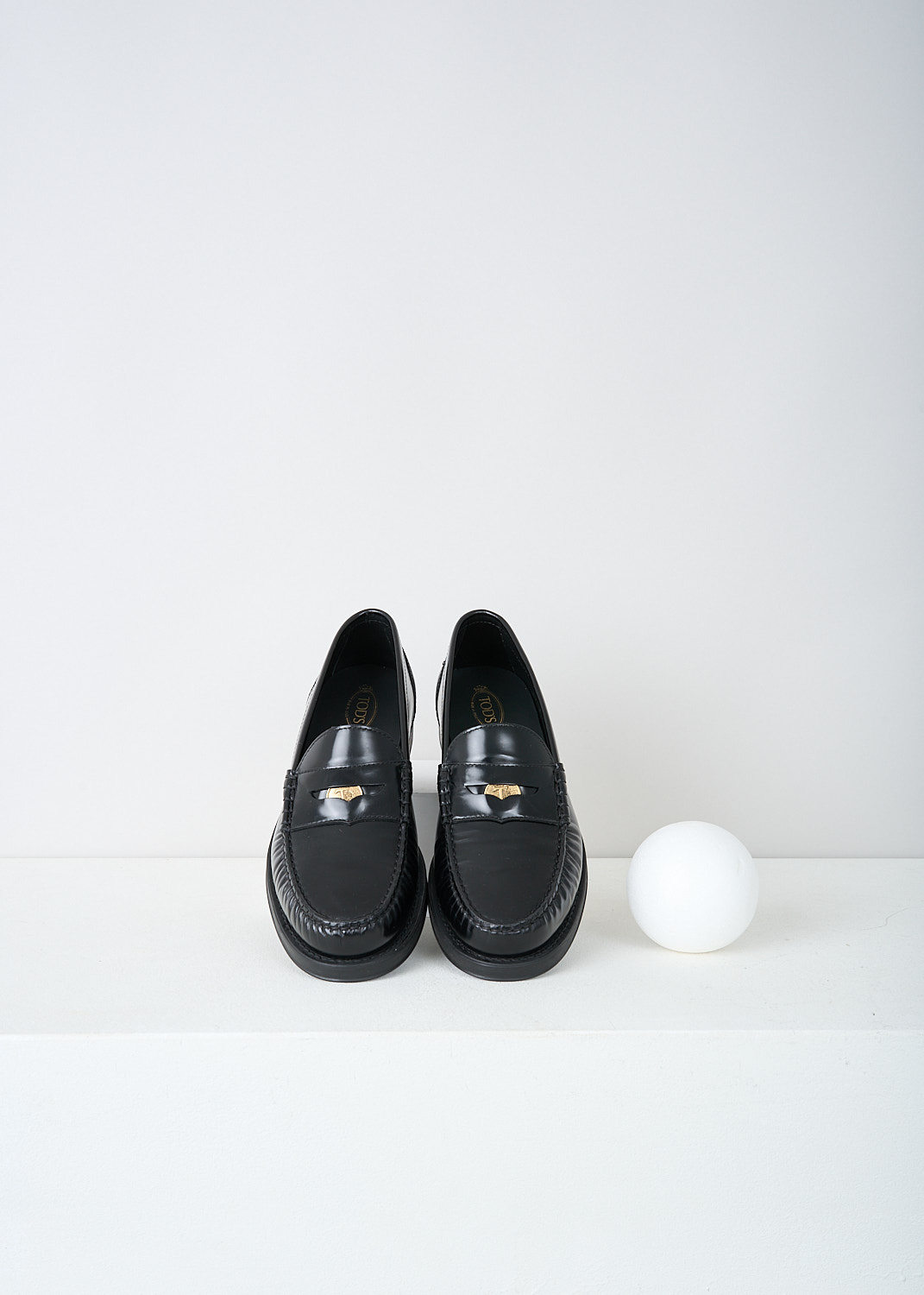 Tods, Black leather penny loafers, XXW02I0EP00SHAB999, Black, Top, These black leather slip-on penny loafers have a rounded toe and a slotted leather strip with a decorative coin over the upper side. Around the trim, the leather is subtly pleated. These loafers have black soles.
  

