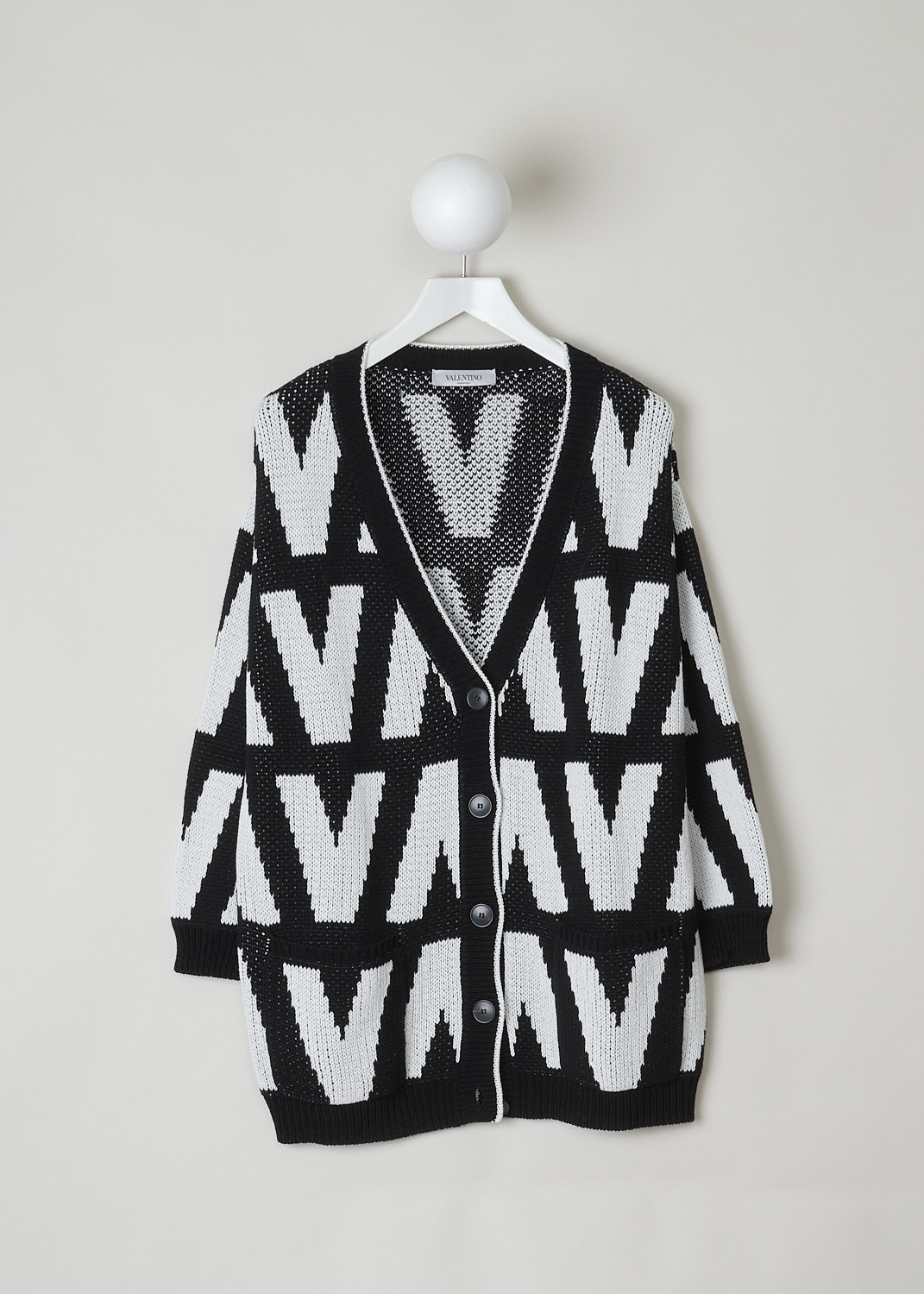 VALENTINO, BLACK AND WHITE CHUNKY KNIT CARDIGAN, WB3KA02I6G4_0NA, Black, White, Print, Front, This chunky knit cardigan has a black and white print with the brand's signature V incorporated in the motif. The cardigan has a ribbed V-neck. That same ribbed finish can be found along the front button closure, on the cuffs and on the hemline. Two patch pockets can be found on the front. The cardigan has an oversized silhouette. 
