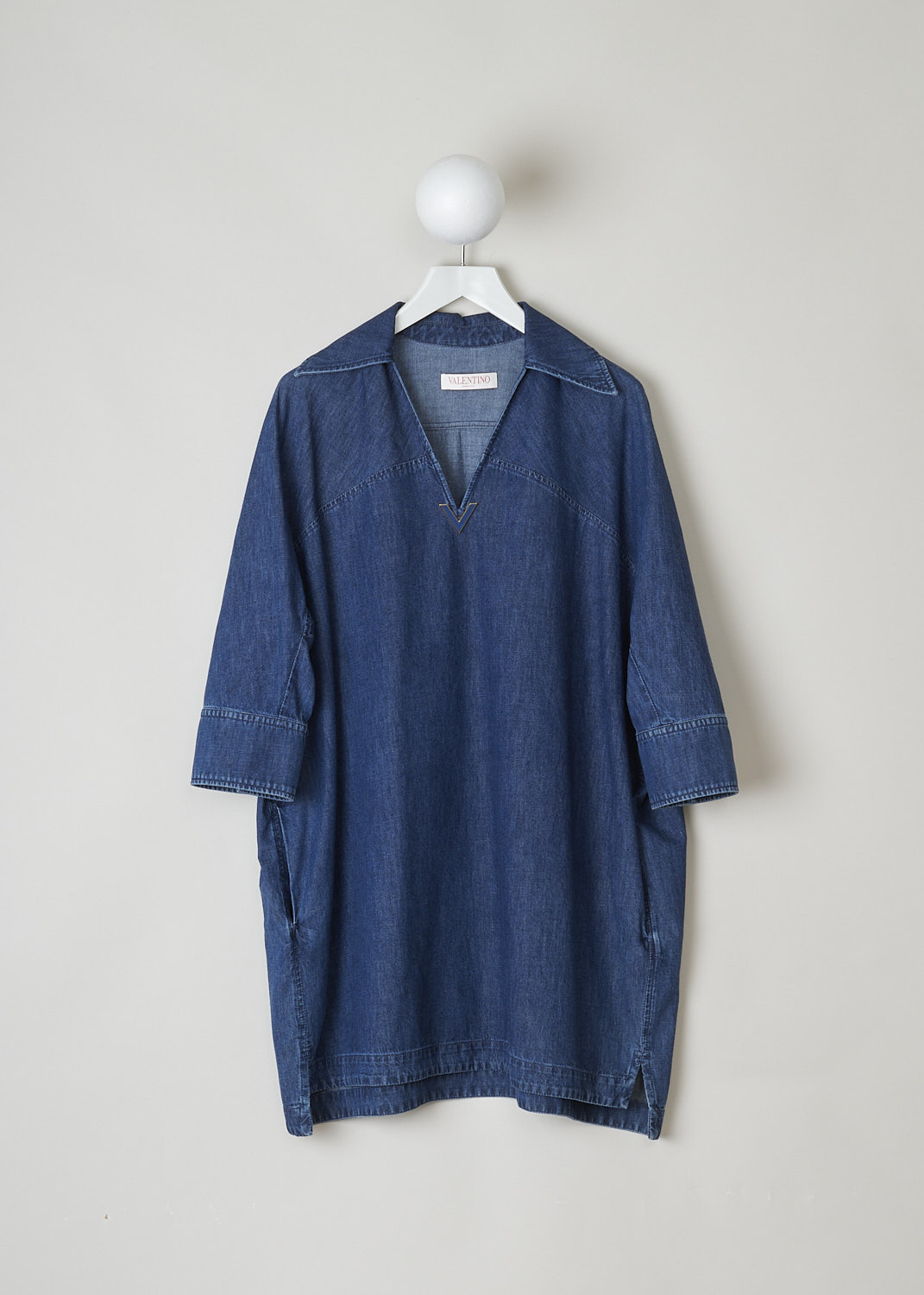 VALENTINO, DARK WASH DENIM TUNIC, XB3DB01I433_558XB3DB01I433_558, Blue, Front, This wide tunic in a darker wash jean fabric has a spread collar with a V-neckline. The end of the V-neck is decorated with the brands signature V. The tunic has three-quarter raglan sleeves with buttoned cuffs. Slanted pockets can be found concealed in the side seams. The tunic has an asymmetrical finish, meaning the back is a little longer than the front. Small slits can be found on either side. 
