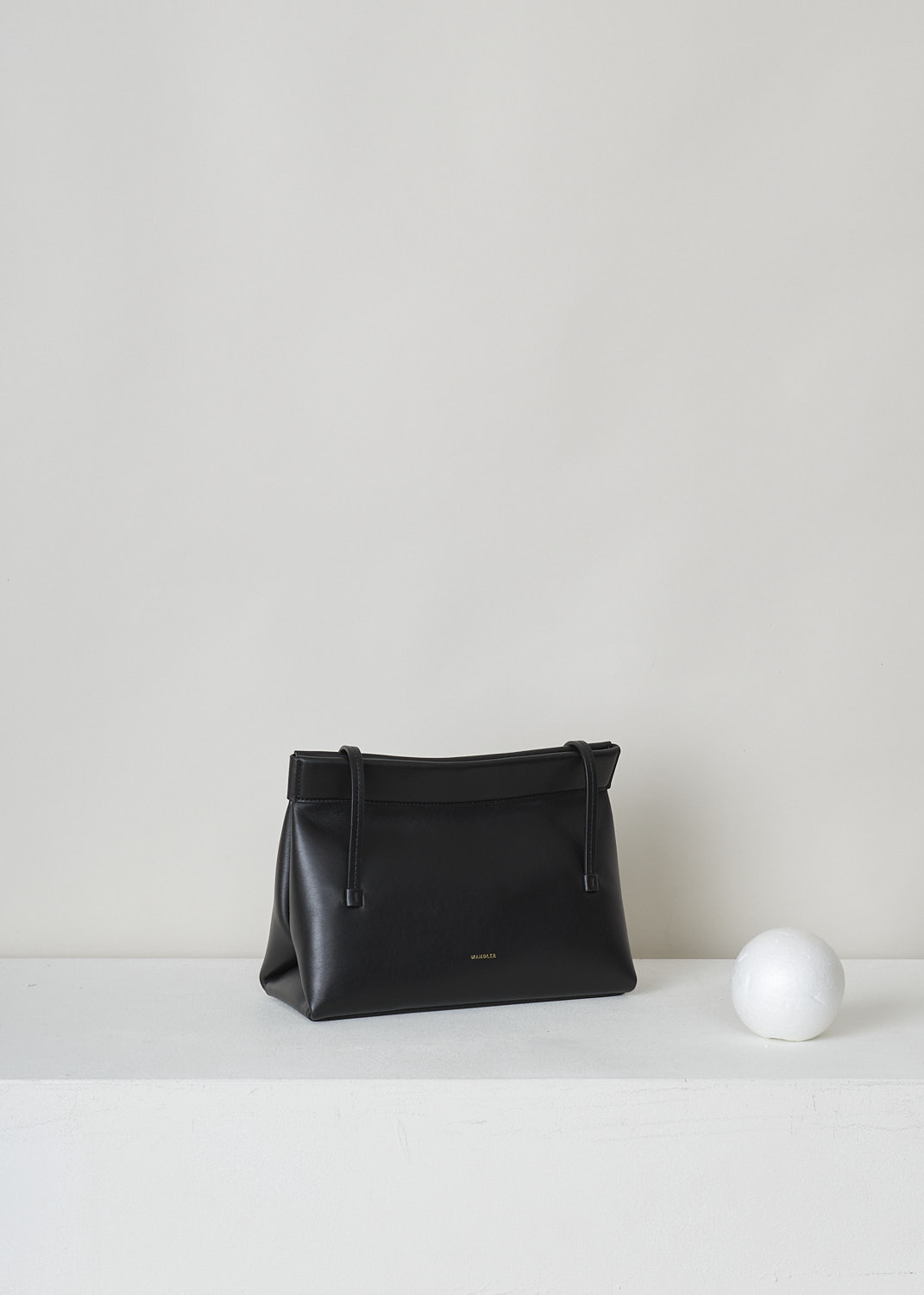 WANDLER, JOANNA MINI BAG IN BLACK, JOANNA_BAG_MINI_BLACK_22108100391, Black, Side, This black Joanna mini hand bag has slim top handles. The magnetic strip closure opens up to the single spacious compartment. On the front, the brand's lettering can be found in gold.  


