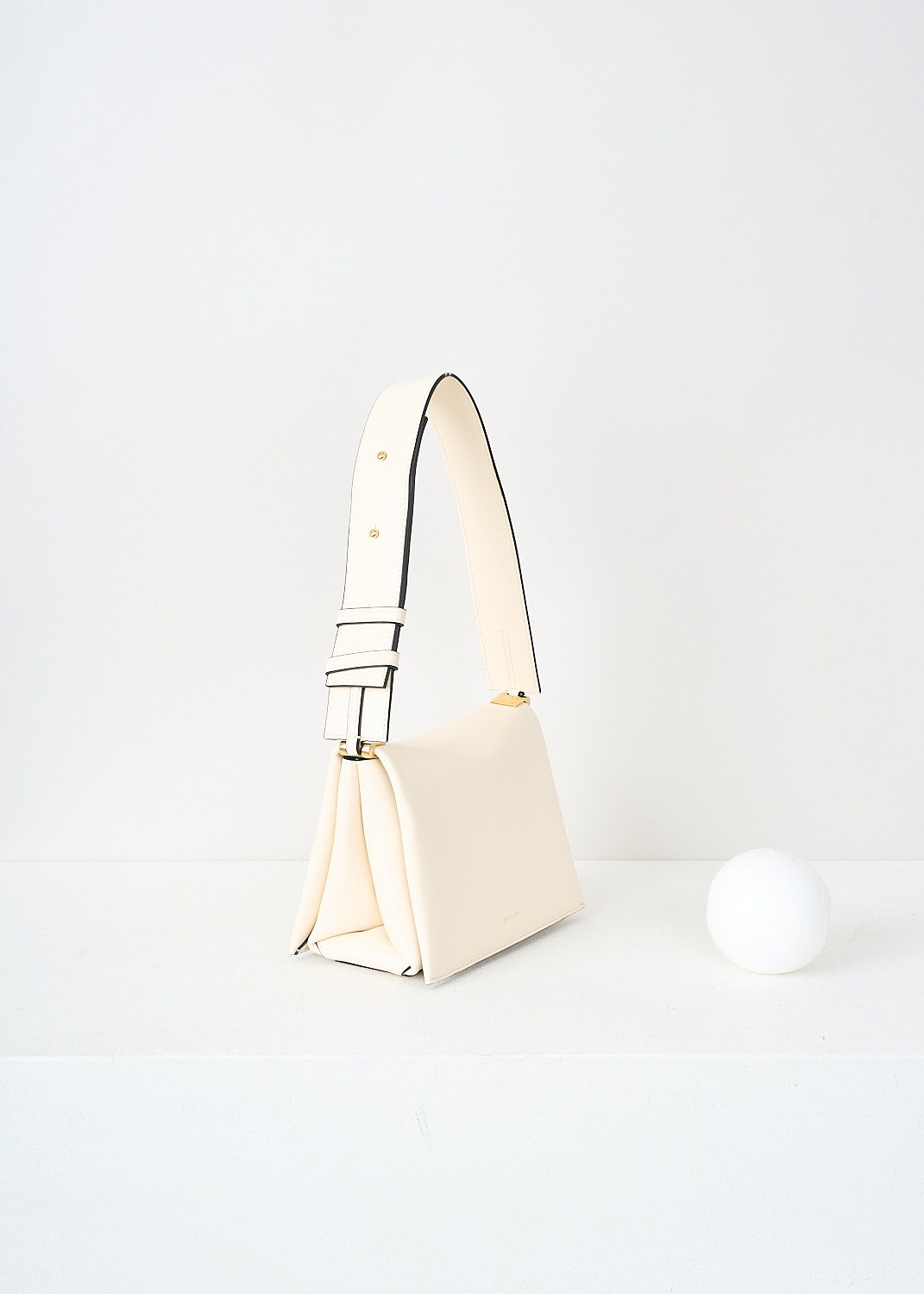 Wandler, Uma box bag in Ivory, UMA_SHOULDER_BOX_IVORY_23102_1093901_1057, White, Side, This Uma box bag in the color Ivory has a broad adjustable shoulder strap. The bag has bulky inward folded corners. On the front, the brands logo can be found embossed in gold. The magnetic flap closure opens up to the two spacious compartments. 

